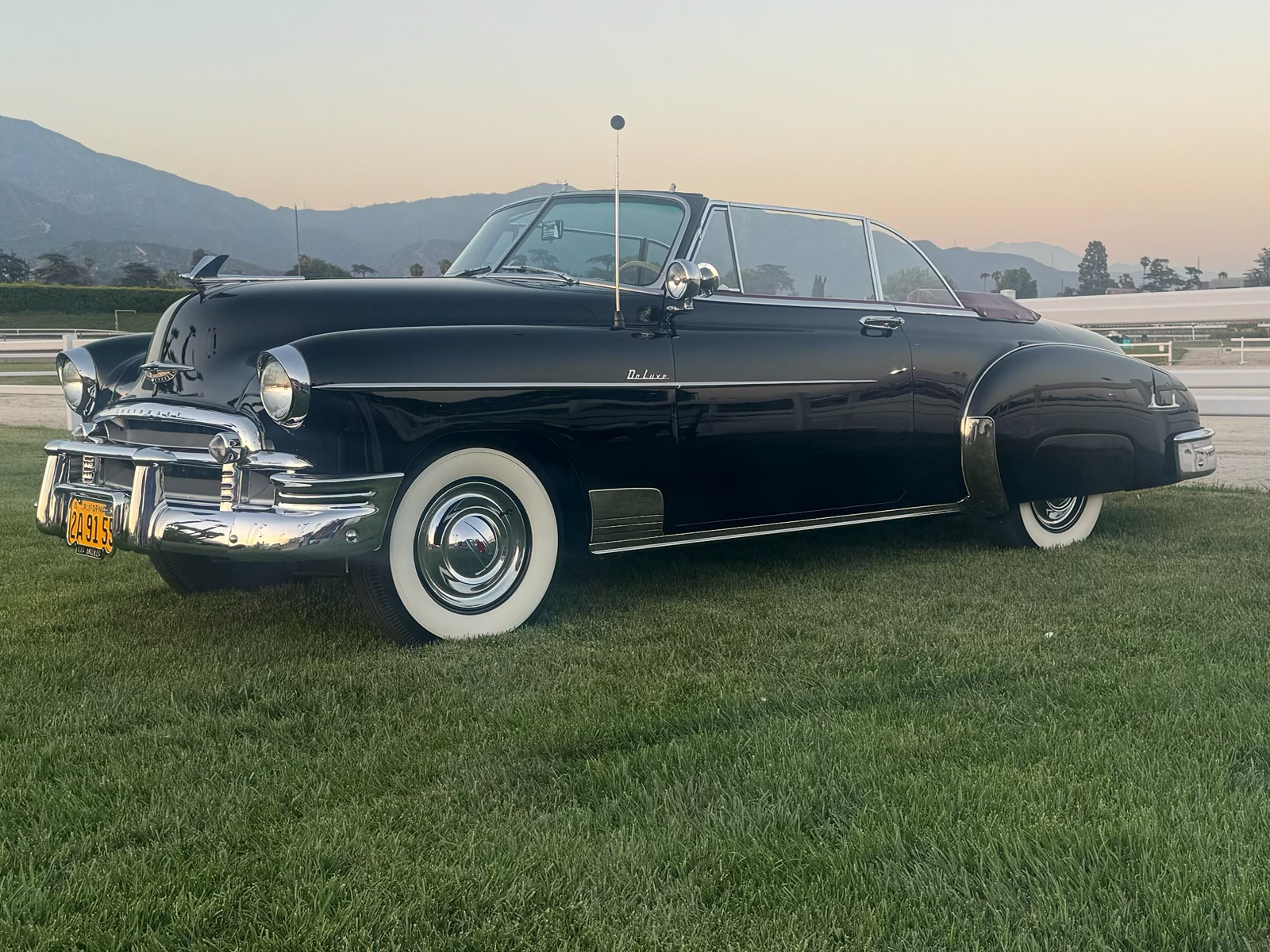 Black convertible by the field.